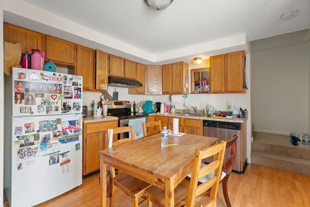 a kitchen with a refrigerator a stove a sink dishwasher and a dining table with wooden floor