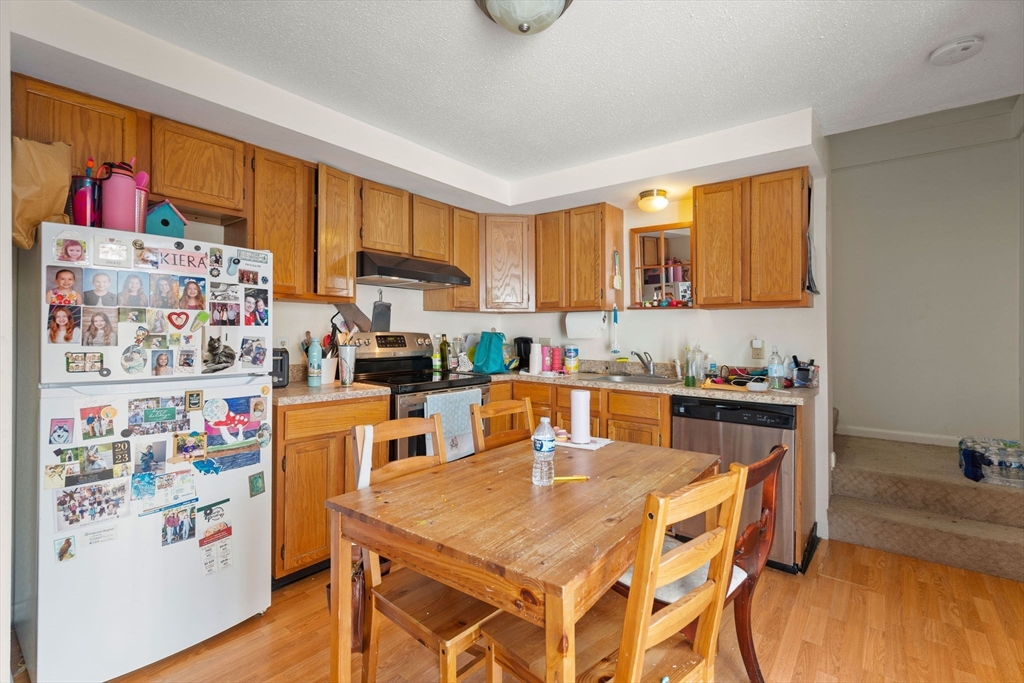 3-5 Roxanne Road Groton, MA 01450 - Photo 17 of 28 a kitchen with a refrigerator a stove a sink dishwasher and a dining table with wooden floor