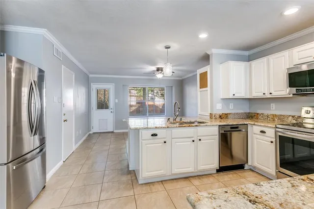 a large white kitchen with stainless steel appliances granite countertop a sink and cabinets