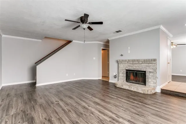 a view of an empty room with wooden floor fireplace and a window