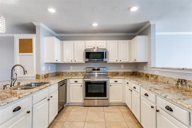 a kitchen with granite countertop white cabinets stainless steel appliances and a sink