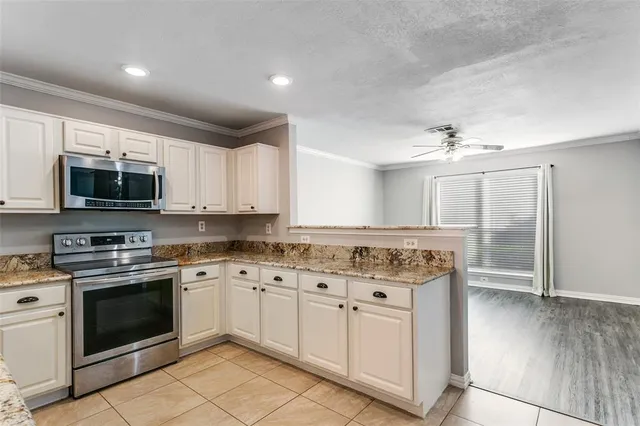 a kitchen with stainless steel appliances granite countertop a stove top oven a sink dishwasher and white cabinets with wooden floor