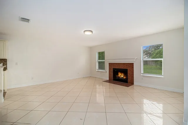 an empty room with windows and fireplace