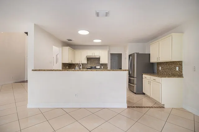 a kitchen with stainless steel appliances granite countertop a refrigerator sink and white cabinets