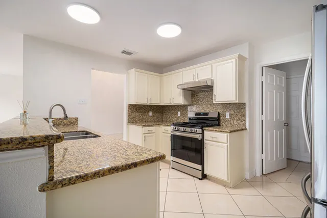 a kitchen with granite countertop a sink stove and refrigerator