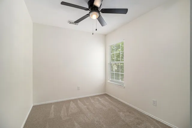 an empty room with windows and fan