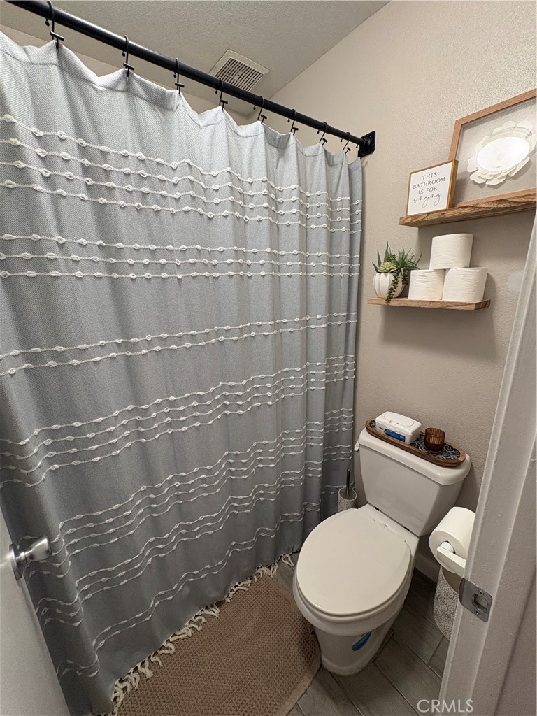 2255 Cahuilla Street, Unit 49 Colton, CA 92324 - Photo 18 of 19 a bathroom with a toilet and a shower curtain