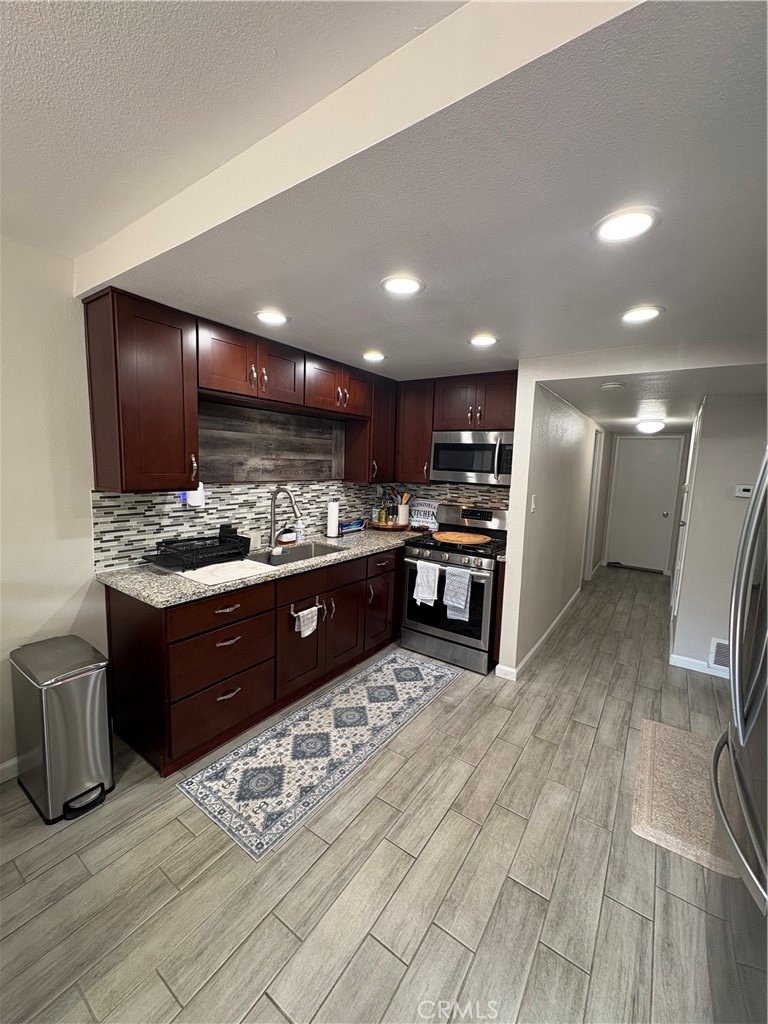 2255 Cahuilla Street, Unit 49 Colton, CA 92324 - Photo 6 of 19 a kitchen with stainless steel appliances kitchen island granite countertop a sink stove and refrigerator