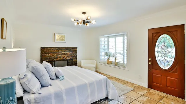 a bedroom with a bed a mirror on the dresser and a chandelier