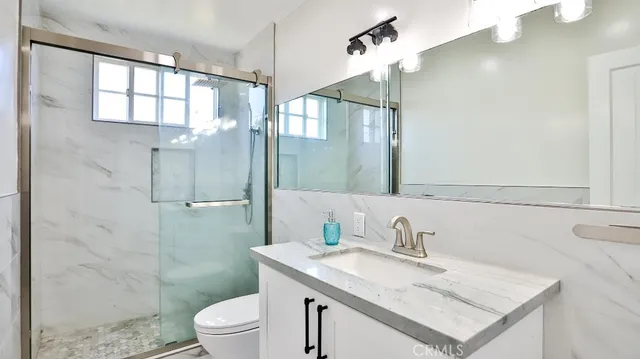 a bathroom with a granite countertop sink toilet a mirror and shower