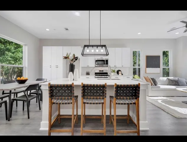 a kitchen with stainless steel appliances kitchen island granite countertop a table chairs and a refrigerator