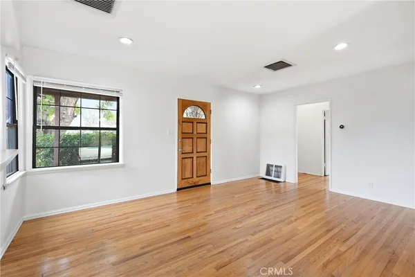 an empty room with wooden floor and windows