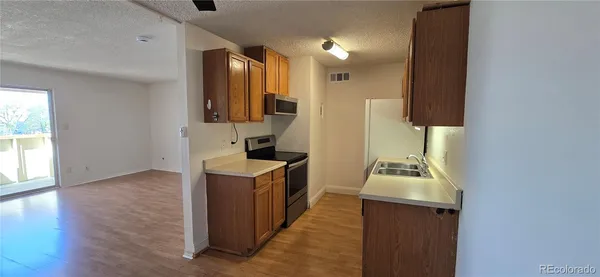 a kitchen with sink a refrigerator and wooden floor