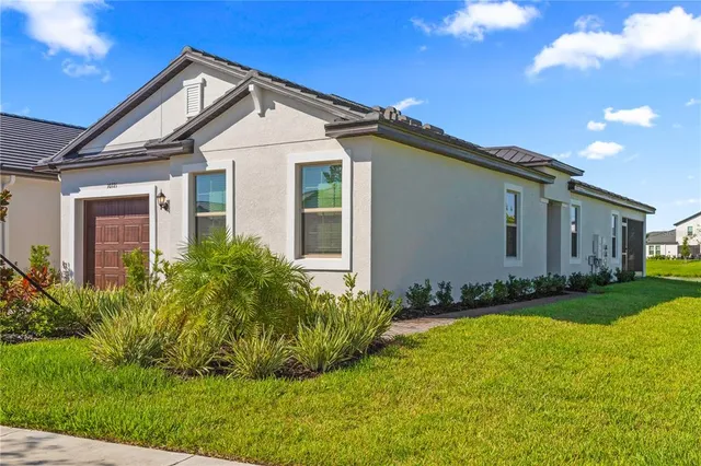 a view of a white house with a big yard and potted plants