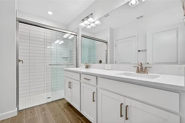 a bathroom with a double vanity sink a mirror and shower