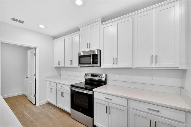 a kitchen with white cabinets and stainless steel appliances