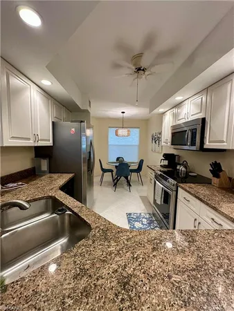 a kitchen with stainless steel appliances granite countertop a sink stove microwave and refrigerator