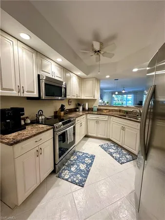 a kitchen with stainless steel appliances granite countertop a stove top oven a sink dishwasher a refrigerator and white cabinets with wooden floor