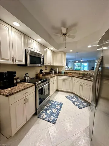 a kitchen with stainless steel appliances granite countertop a stove top oven a sink dishwasher a refrigerator and white cabinets with wooden floor