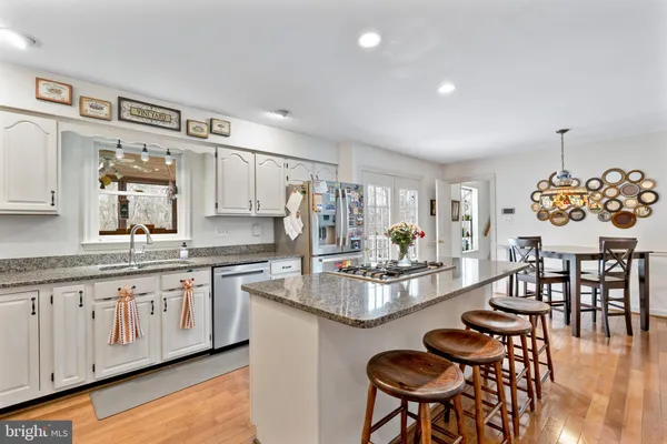 a kitchen with stainless steel appliances granite countertop a table and chairs in it