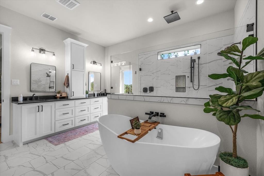 1059 Sweeney Way Weatherford, TX 76087 - Photo 14 of 37 Primary bathroom featuring a freestanding soaking tub, a spacious glass-enclosed shower with multiple showerheads, and large format marble-look tile flooring