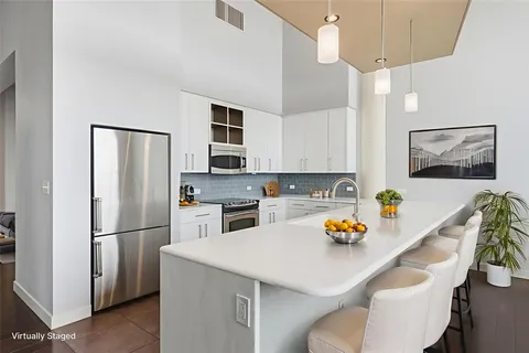 a kitchen with stainless steel appliances a refrigerator a sink a stove a dining table and chairs