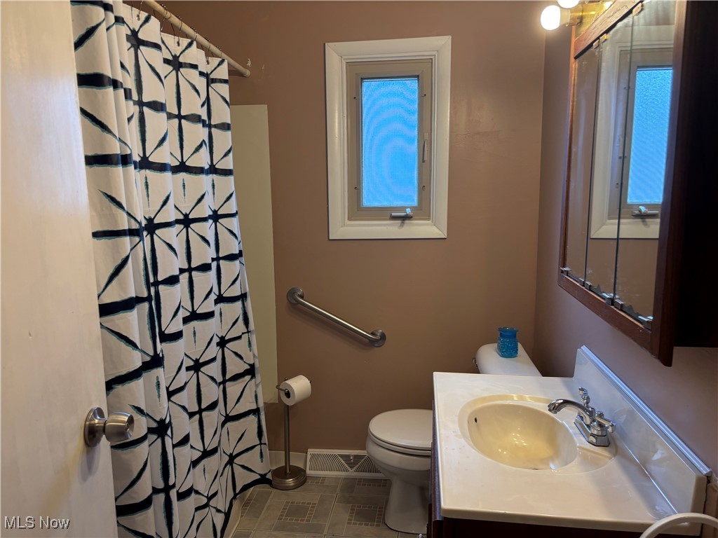 115 Lee Road Painesville, OH 44077 - Photo 16 of 19 Full bathroom featuring vanity, toilet, a shower with shower curtain, baseboards, and visible vents