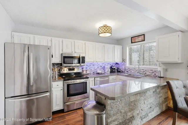 a kitchen with granite countertop a stove a sink dishwasher a refrigerator and a oven with wooden floor