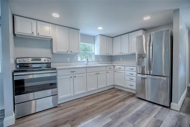 a kitchen with white cabinets stainless steel appliances and wooden floor