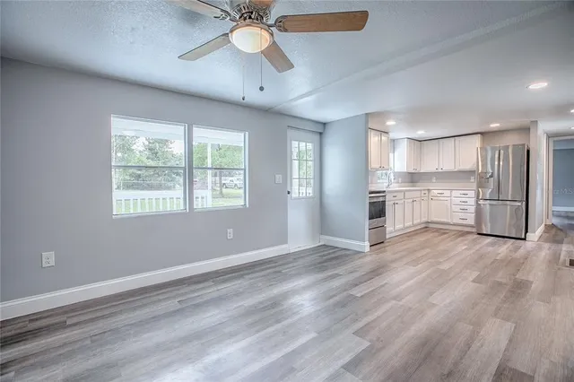 a view of an empty room with a window and wooden floor