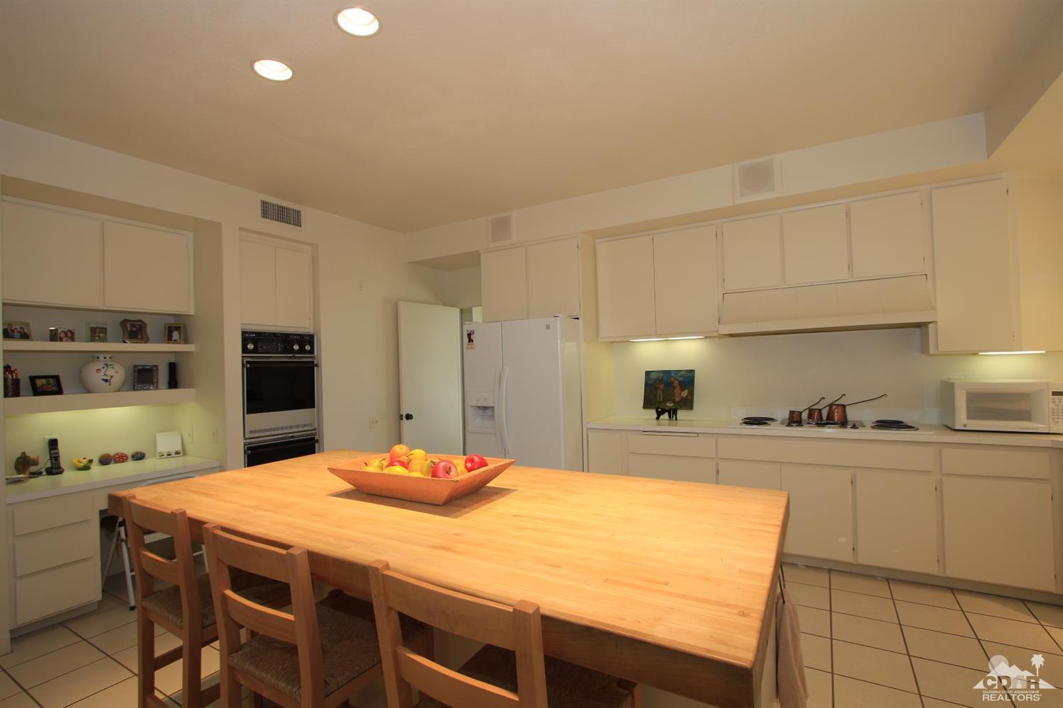 927 Inverness Drive Rancho Mirage, CA 92270 - Photo 9 of 42 a kitchen with a table chairs refrigerator and cabinets