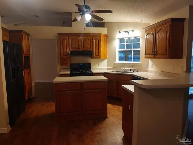 a kitchen with granite countertop a sink cabinets stainless steel appliances and a window