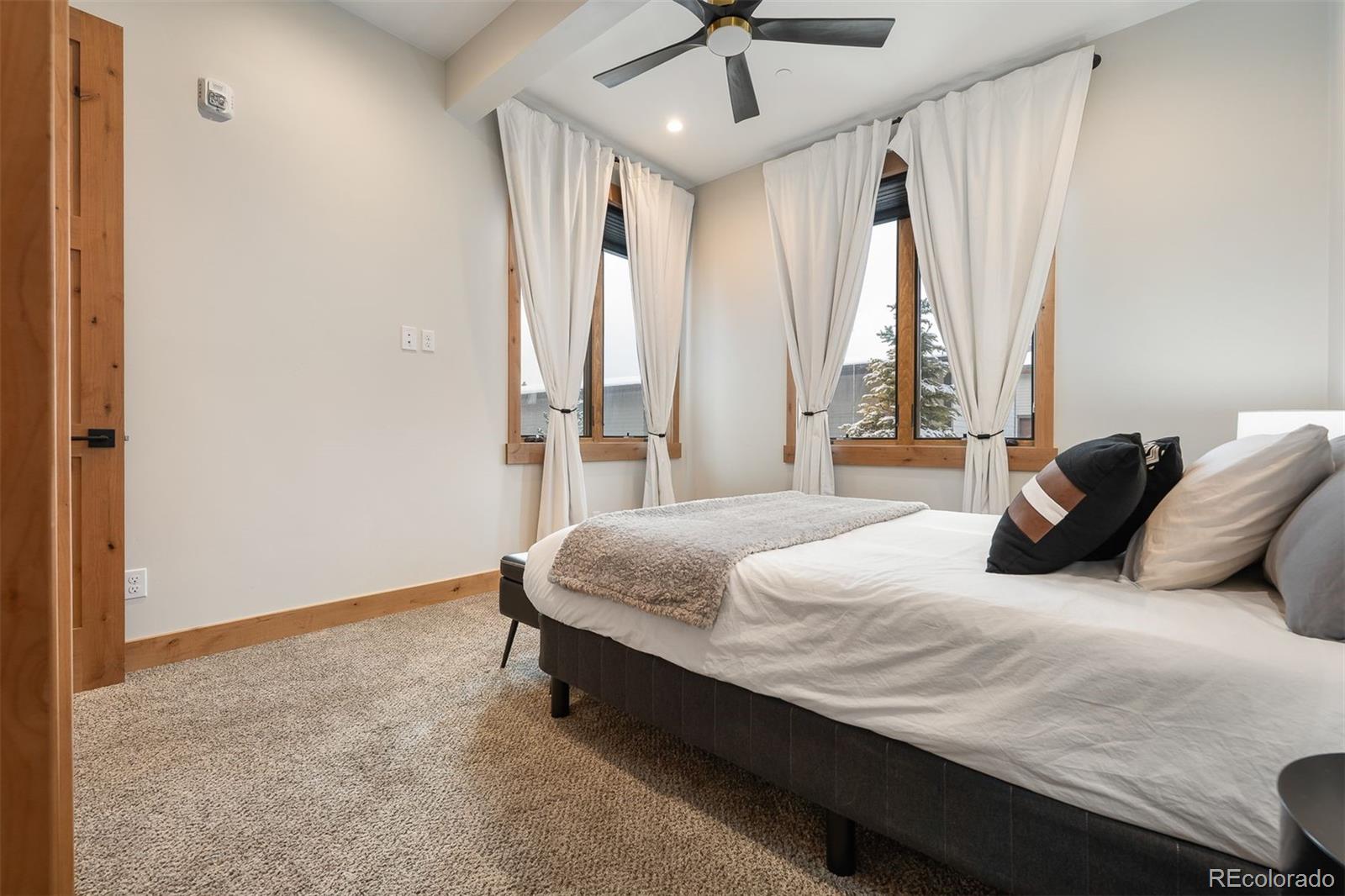 72 Meadow Trail, Unit F102 Fraser, CO 80442 - Photo 22 of 35 a bedroom with a bed and large windows