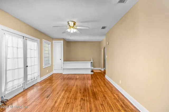 a view of an empty room with a window and wooden floor