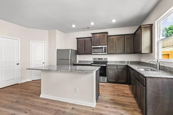a kitchen with stainless steel appliances granite countertop a sink stove and refrigerator
