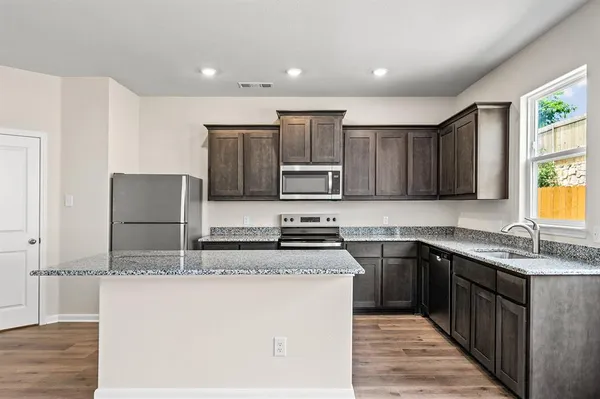 a kitchen with stainless steel appliances granite countertop a sink stove microwave and refrigerator