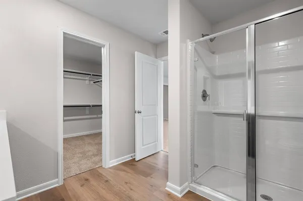 a bathroom with a walk in closet and wooden floor