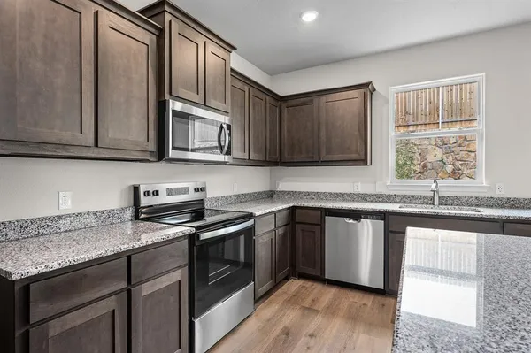 a kitchen with stainless steel appliances granite countertop wooden cabinets a sink and a stove