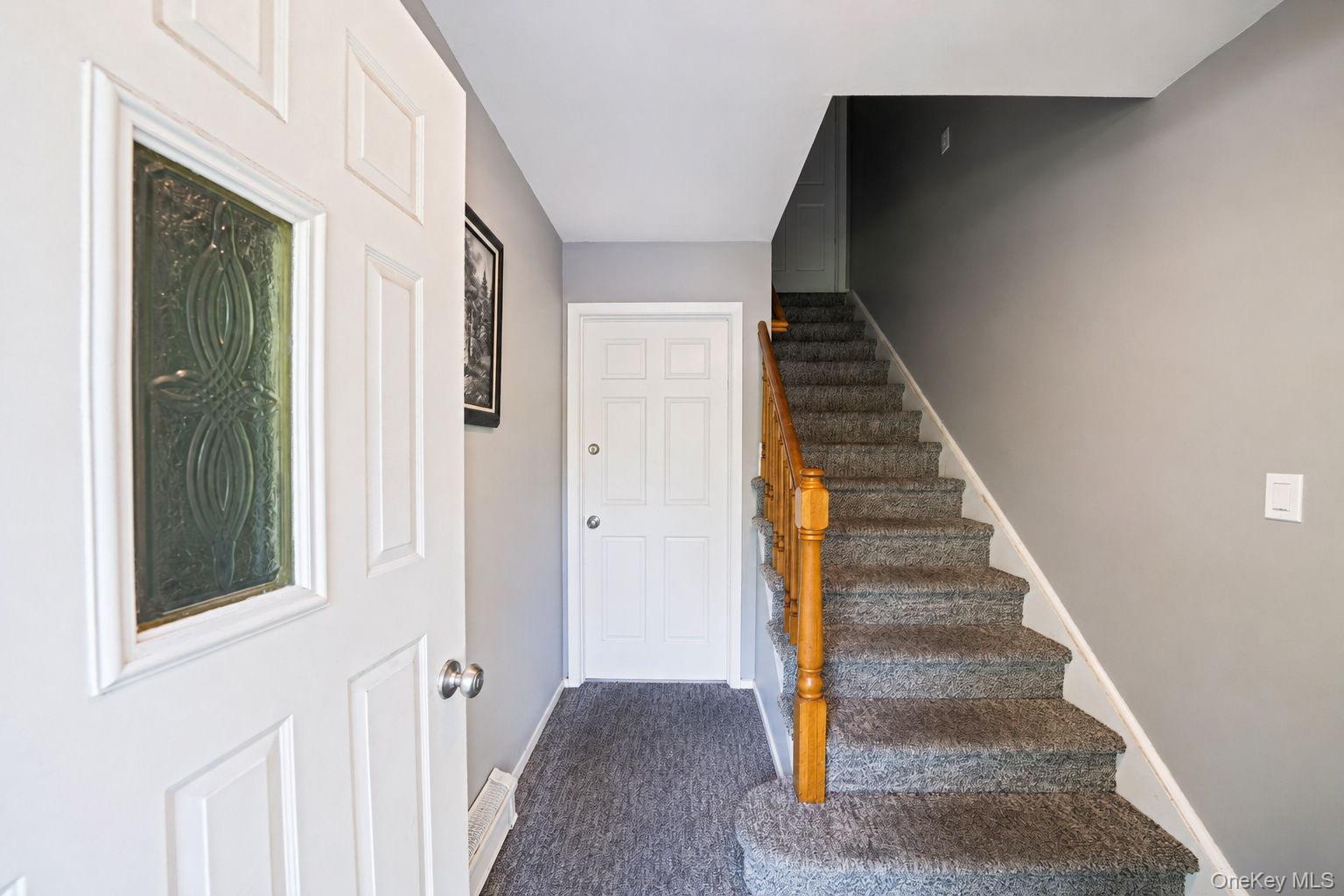 31 Crooked Hill Road Huntington, NY 11743 - Photo 21 of 32 Entryway featuring a decorative glass-paneled door, textured carpeting, a white paneled door, and a staircase with wood-finish handrail and carpeted treads