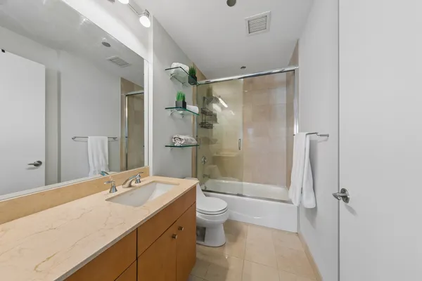 a bathroom with a granite countertop sink toilet and shower glass cabinet