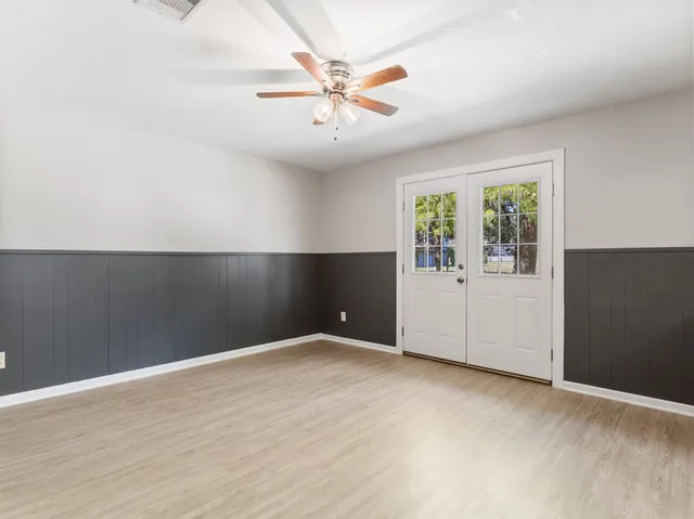 an empty room with windows and ceiling fan