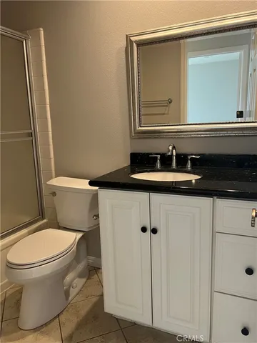 a bathroom with a granite countertop toilet sink and mirror