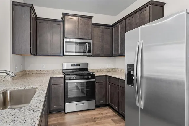 a kitchen with stainless steel appliances granite countertop a refrigerator stove and sink
