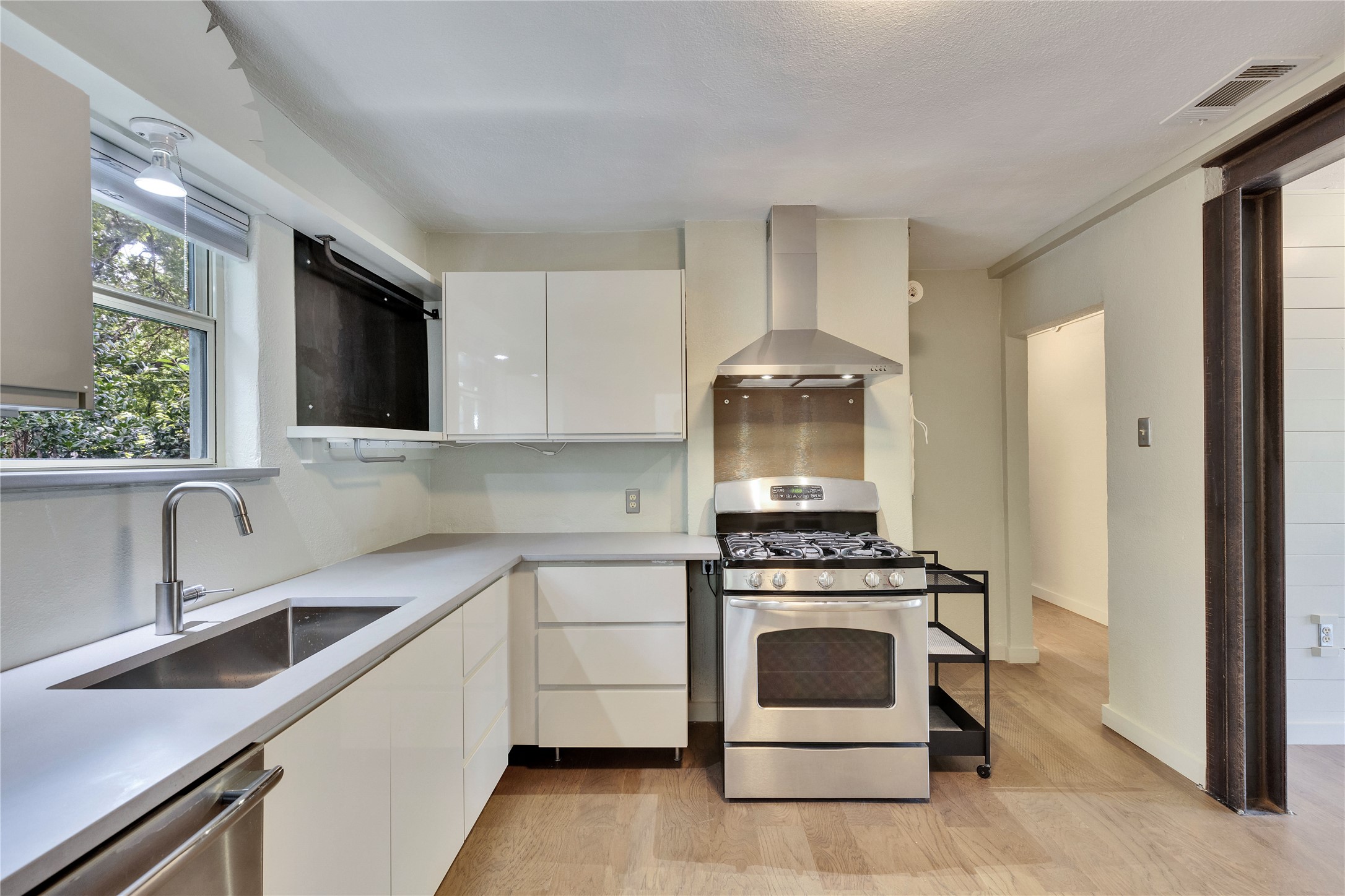1306 Norwood Road, Unit A Austin, TX 78722 - Photo 9 of 21 A well-appointed culinary space featuring sleek cabinetry, modern appliances, and rich wood flooring.