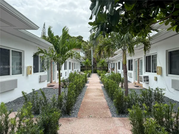 a view of a house with a small yard plants and large tree