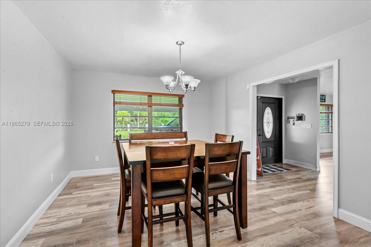 19926 Southwest 326th Street Homestead, FL 33030 - Photo 12 of 46 a dining room with furniture a chandelier and wooden floor