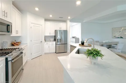 a kitchen with stainless steel appliances kitchen island granite countertop a refrigerator and a sink