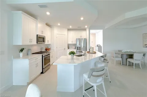 a large white kitchen with a stove a sink a refrigerator and a dining table