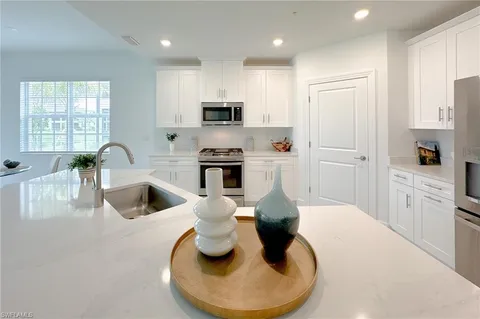 a open kitchen with white cabinets and white appliances