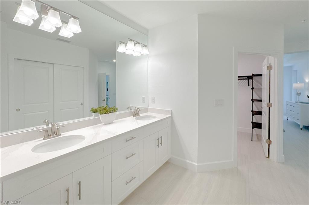 16881 Fairgrove Way, Unit 7102 Naples, FL 34110 - Photo 18 of 50 a bathroom with a double vanity sink a mirror and a shower